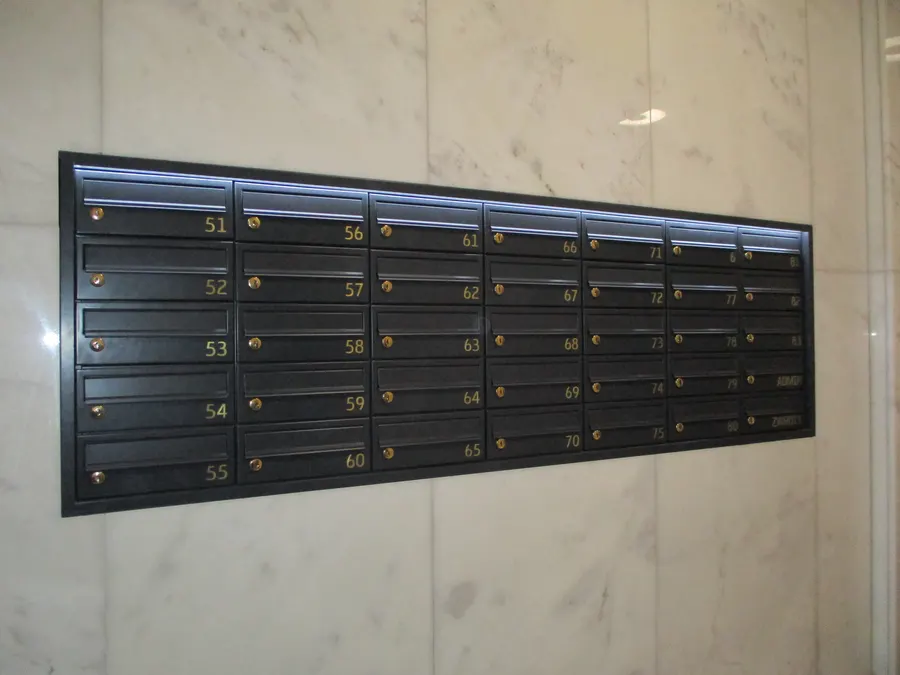 Boîtes aux lettres encastrées noires dans un hall en marbre